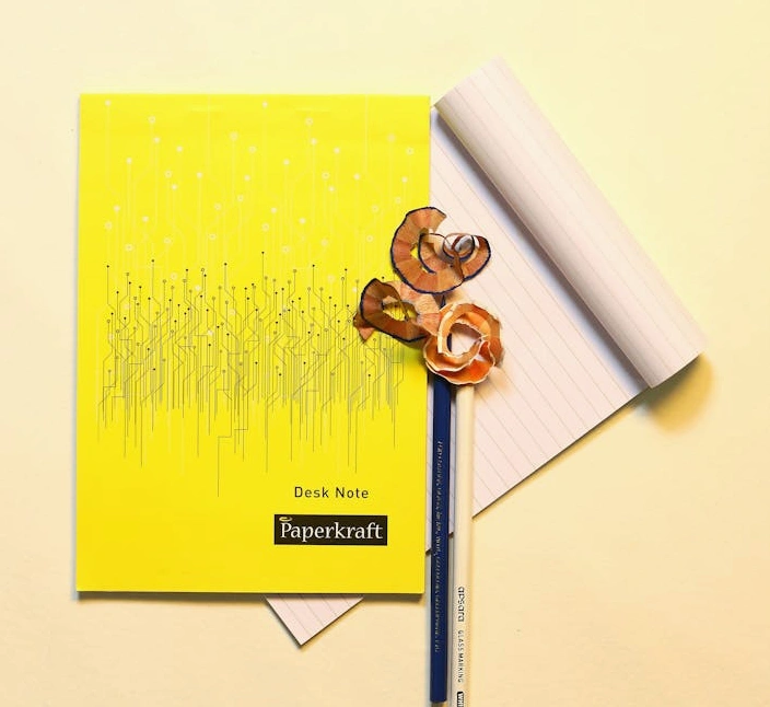 Osoba zapisující si strategické poznámky do zápisníku na pracovním stole.